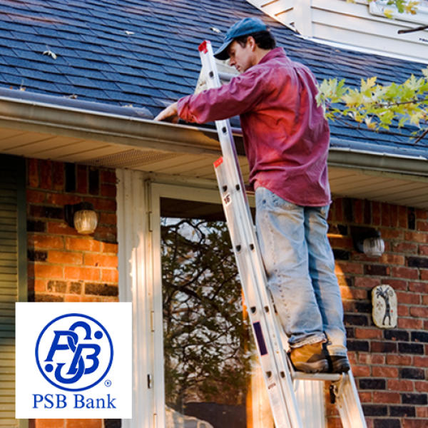 Man on ladder clearing leaves out of the gutter of his house