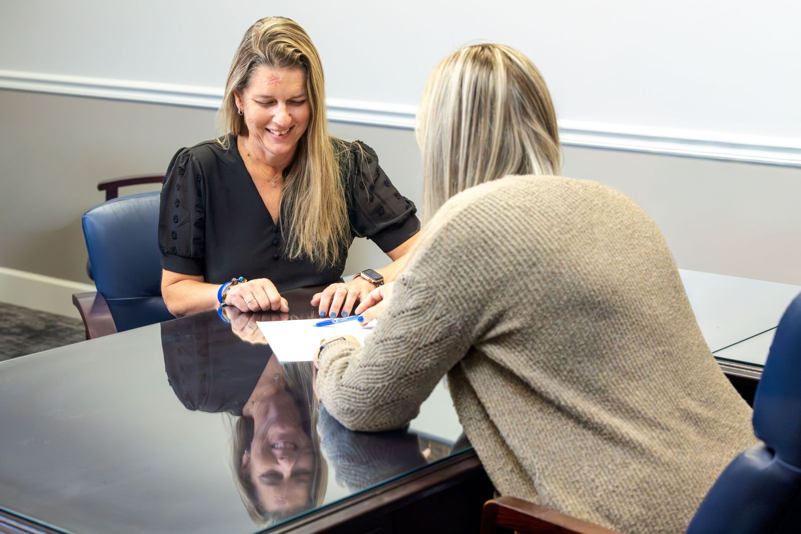 PSB Bank employee meeting with a customer and reviewing documents together at a table inside a bank branch.